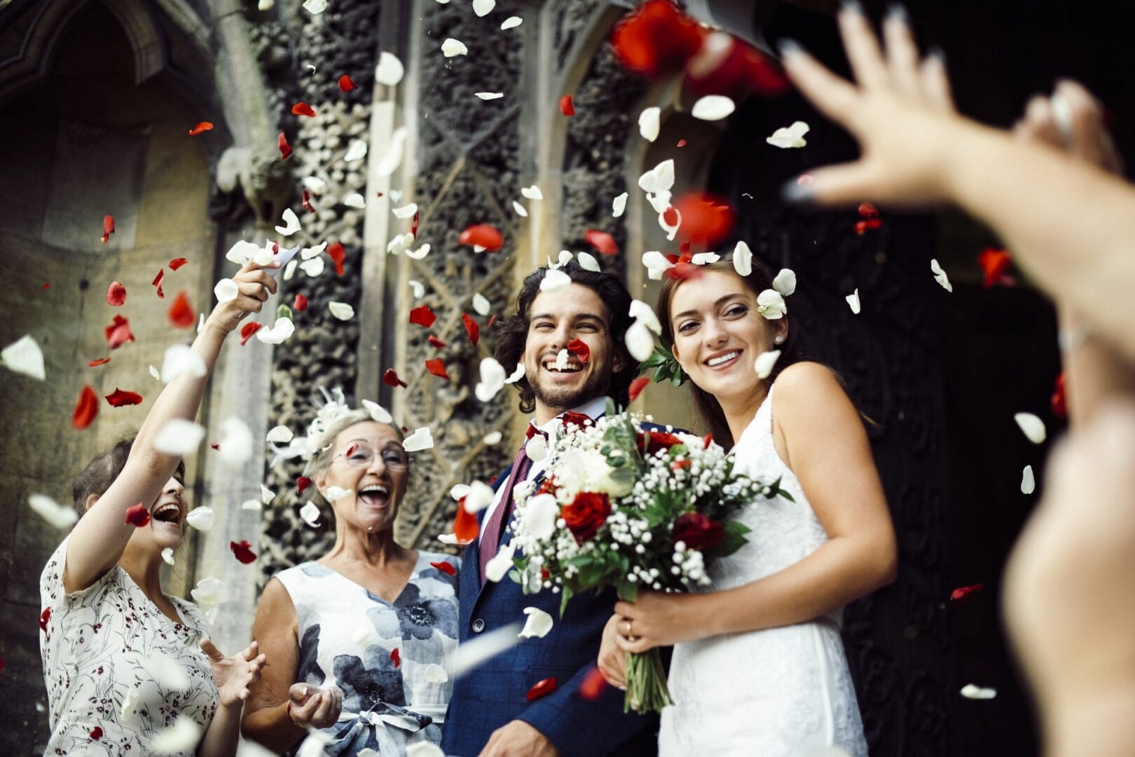 Family throwing rose petals at the newly wed bride and groom